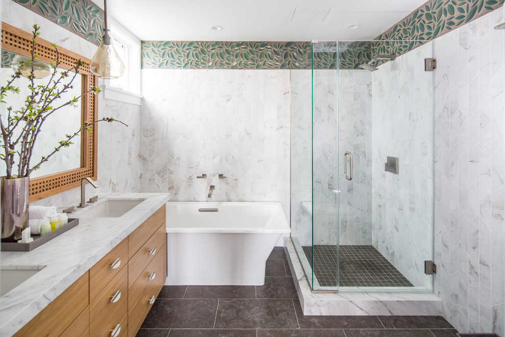 This is an example of a transitional master bathroom in Orange County with flat-panel cabinets, medium wood cabinets, a freestanding tub, a corner shower, white tile, an undermount sink, grey floor and white benchtops.