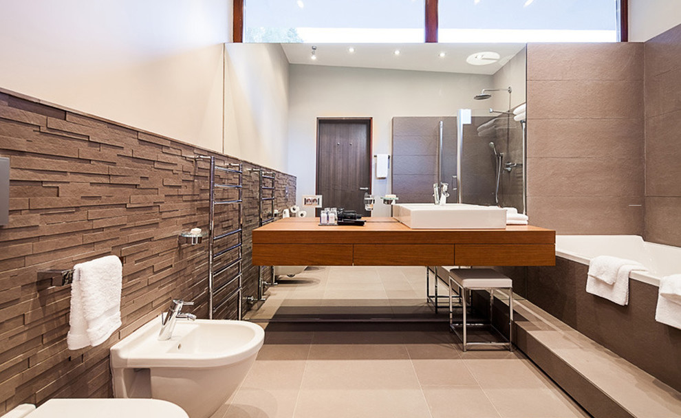 This is an example of a mid-sized modern master bathroom in Moscow with flat-panel cabinets, medium wood cabinets, an undermount tub, a corner shower, a wall-mount toilet, beige tile, porcelain tile, beige walls, porcelain floors, a drop-in sink, wood benchtops, beige floor, a hinged shower door and brown benchtops.