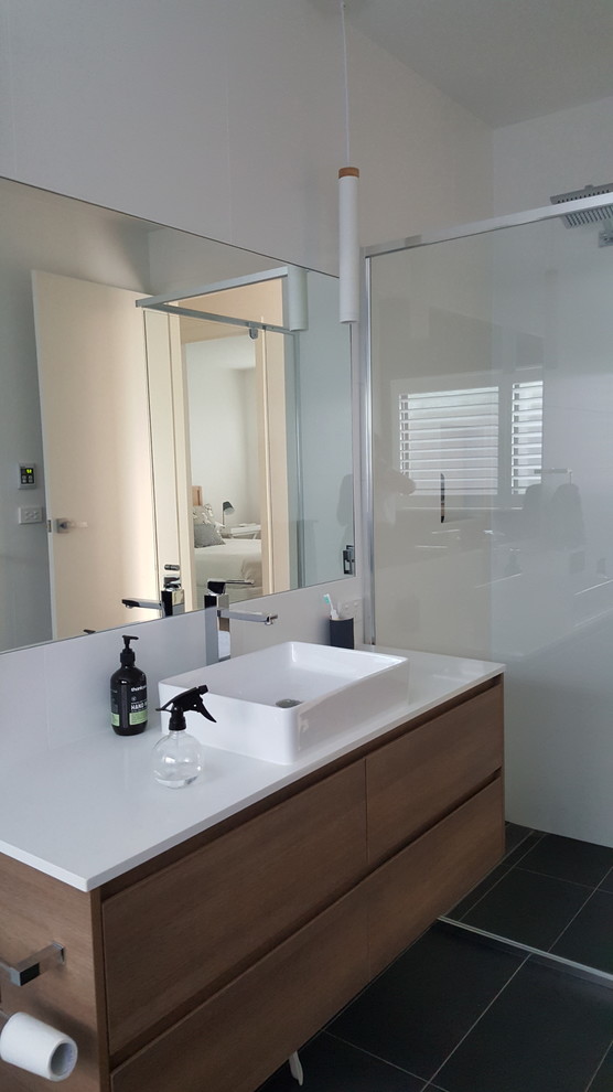 Photo of a mid-sized modern master bathroom in Sydney with flat-panel cabinets, white cabinets, an alcove shower, white tile, porcelain tile, white walls, porcelain floors, an integrated sink, granite benchtops, black floor and a hinged shower door.