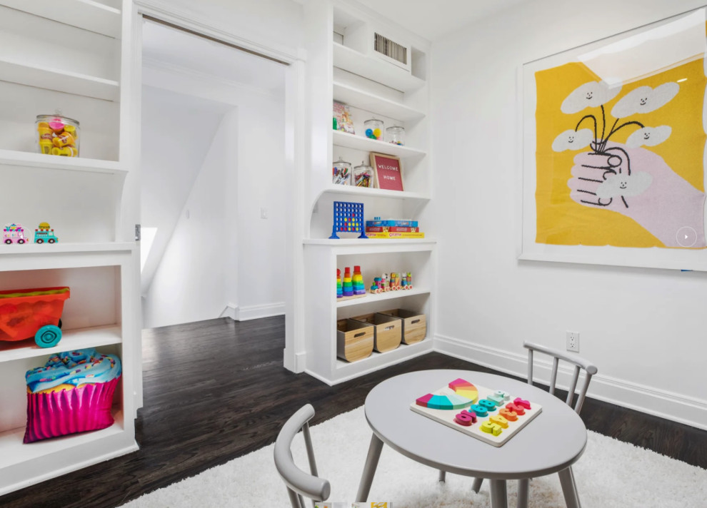 This is an example of a mid-sized transitional gender-neutral kids' room in Los Angeles with white walls, dark hardwood floors and white floor.