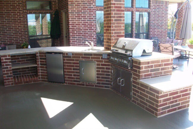 Photo of a mid-sized modern backyard patio in Oklahoma City with an outdoor kitchen, stamped concrete and a roof extension.