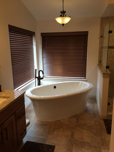 This is an example of a mid-sized traditional master bathroom in Denver with raised-panel cabinets, medium wood cabinets, a freestanding tub, a corner shower, beige walls, laminate floors, an undermount sink, granite benchtops, beige floor and a hinged shower door.