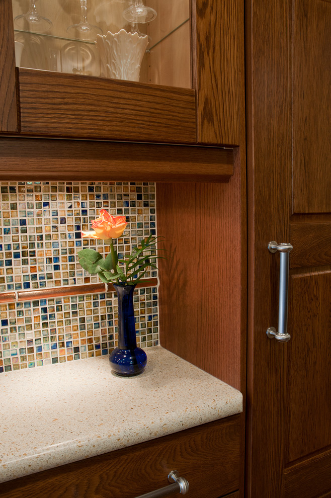 Eat-in kitchen - mid-sized transitional u-shaped medium tone wood floor eat-in kitchen idea in San Diego with an integrated sink, raised-panel cabinets, medium tone wood cabinets, solid surface countertops, stainless steel appliances, multicolored backsplash, mosaic tile backsplash and a peninsula