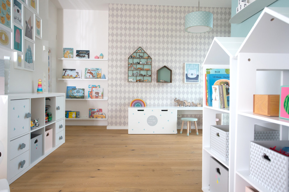 Mid-sized scandinavian gender-neutral kids' room in Hamburg with white walls, medium hardwood floors and beige floor.