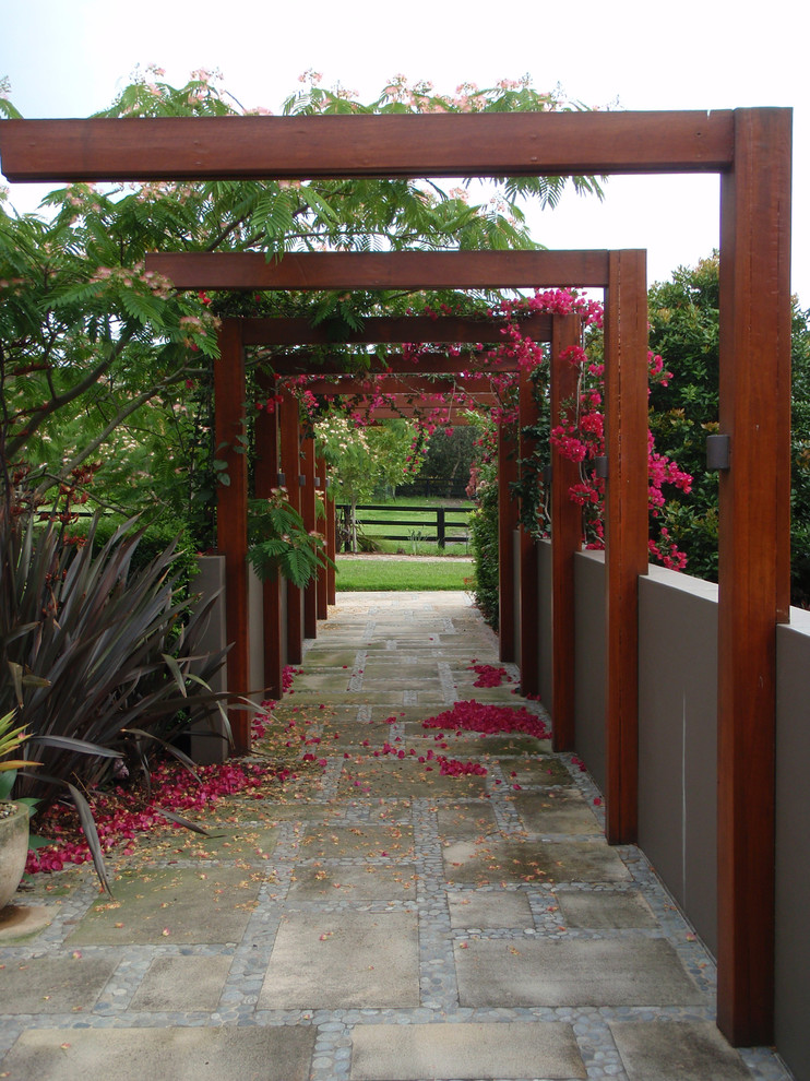 This is an example of a tropical front yard partial sun garden for spring in Sydney with a garden path and concrete pavers.