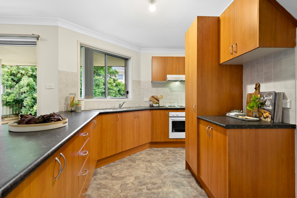Design ideas for a large contemporary l-shaped open plan kitchen in Sydney with a double-bowl sink, medium wood cabinets, white splashback, ceramic splashback, lino flooring, grey floors and grey worktops.