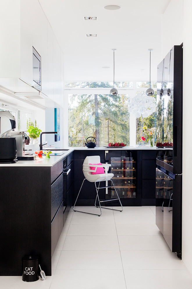 This is an example of a large scandinavian l-shaped kitchen in Stockholm with flat-panel cabinets, dark wood cabinets, a single-bowl sink, black appliances, limestone floors and no island.