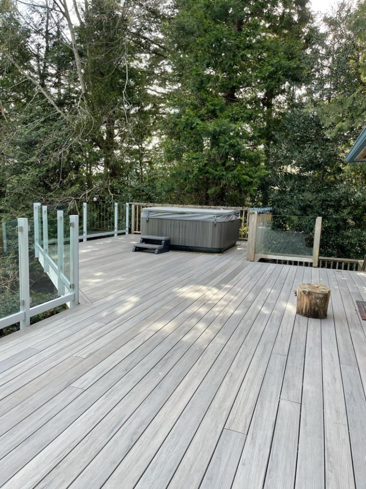 This is an example of a mid-sized contemporary courtyard deck in Vancouver with no cover and glass railing.