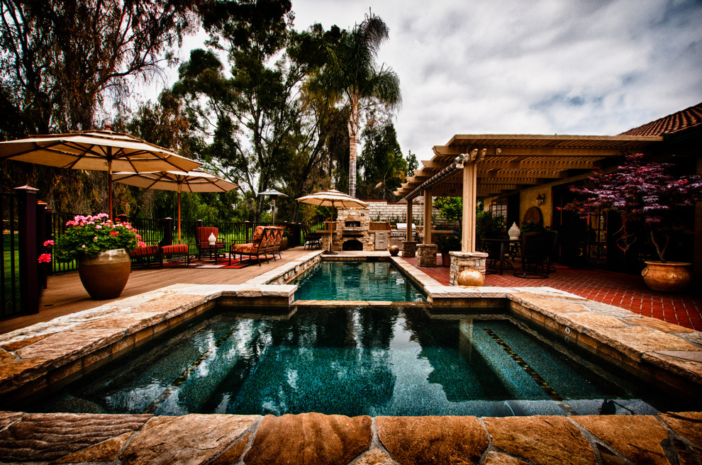 Photo of a mid-sized transitional backyard rectangular lap pool in Los Angeles with a hot tub and natural stone pavers.