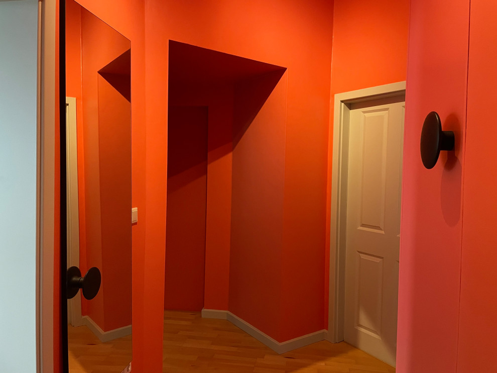 Foto på en mellanstor funkis hall, med rosa väggar, mellanmörkt trägolv och brunt golv