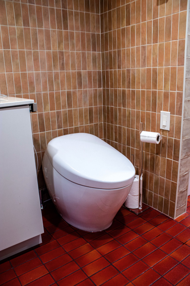 Exempel på ett mellanstort retro beige beige en-suite badrum, med släta luckor, beige skåp, ett badkar i en alkov, en kantlös dusch, en toalettstol med hel cisternkåpa, brun kakel, keramikplattor, beige väggar, klinkergolv i keramik, ett undermonterad handfat, bänkskiva i kvarts, rött golv och dusch med gångjärnsdörr