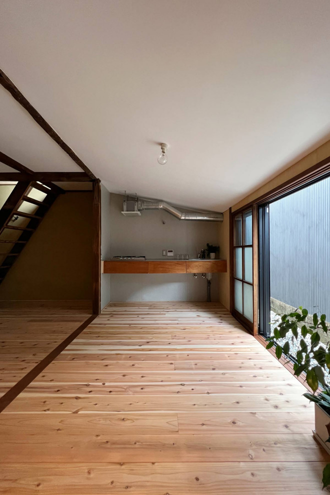 Inredning av ett litet brun linjärt brunt kök och matrum, med en integrerad diskho, öppna hyllor, stänkskydd med metallisk yta, stänkskydd i cementkakel, ljust trägolv och brunt golv
