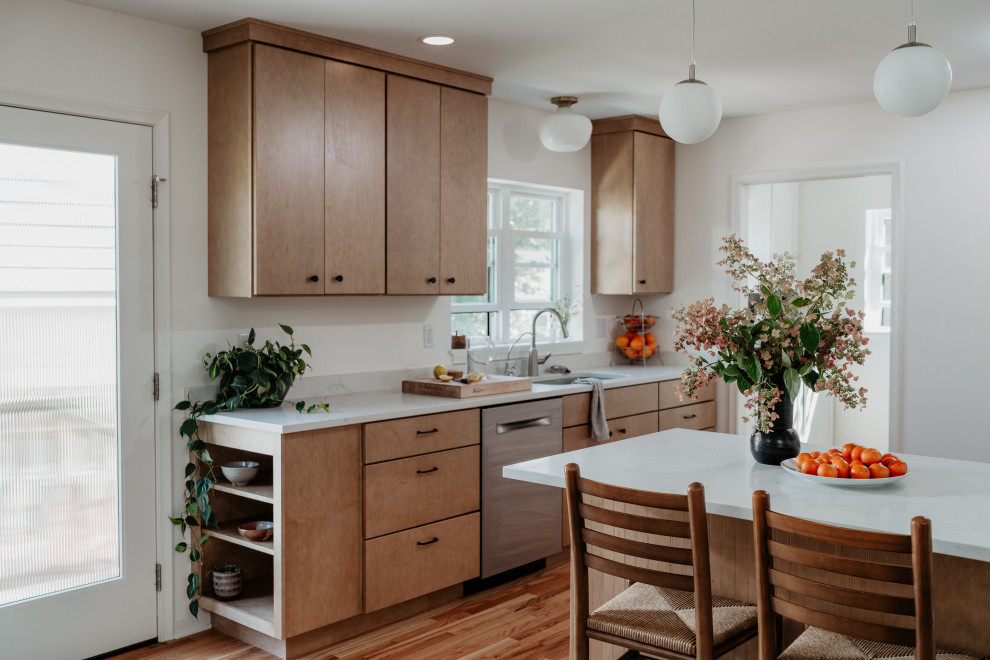 Example of a mid-sized mid-century modern l-shaped medium tone wood floor kitchen pantry design in Detroit with an undermount sink, flat-panel cabinets, light wood cabinets, quartz countertops, white backsplash, quartz backsplash, stainless steel appliances, a peninsula and white countertops