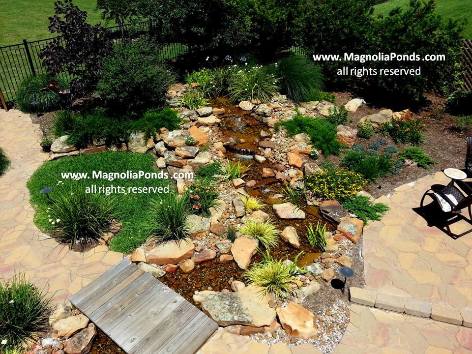 Photo of a large traditional partial sun backyard brick water fountain landscape in Houston.