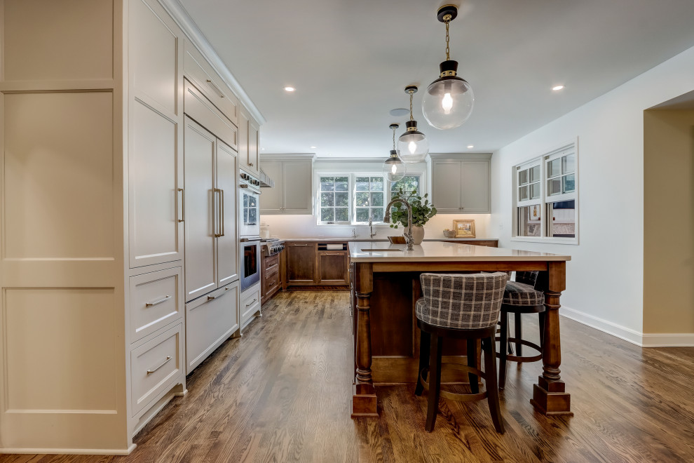 Mid-sized transitional l-shaped medium tone wood floor and brown floor enclosed kitchen photo in Milwaukee with an undermount sink, recessed-panel cabinets, beige cabinets, quartz countertops, white backsplash, ceramic backsplash, stainless steel appliances, an island and white countertops