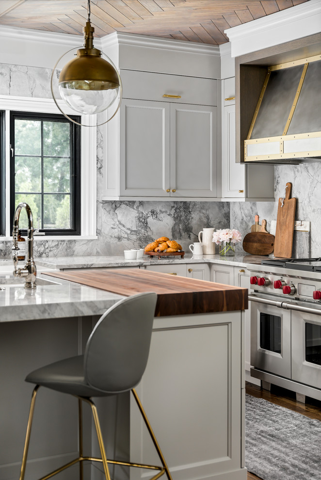 Inspiration for a mid-sized transitional medium tone wood floor and brown floor enclosed kitchen remodel in Chicago with a farmhouse sink, recessed-panel cabinets, gray cabinets, quartzite countertops, gray backsplash, stone slab backsplash, paneled appliances, an island and gray countertops