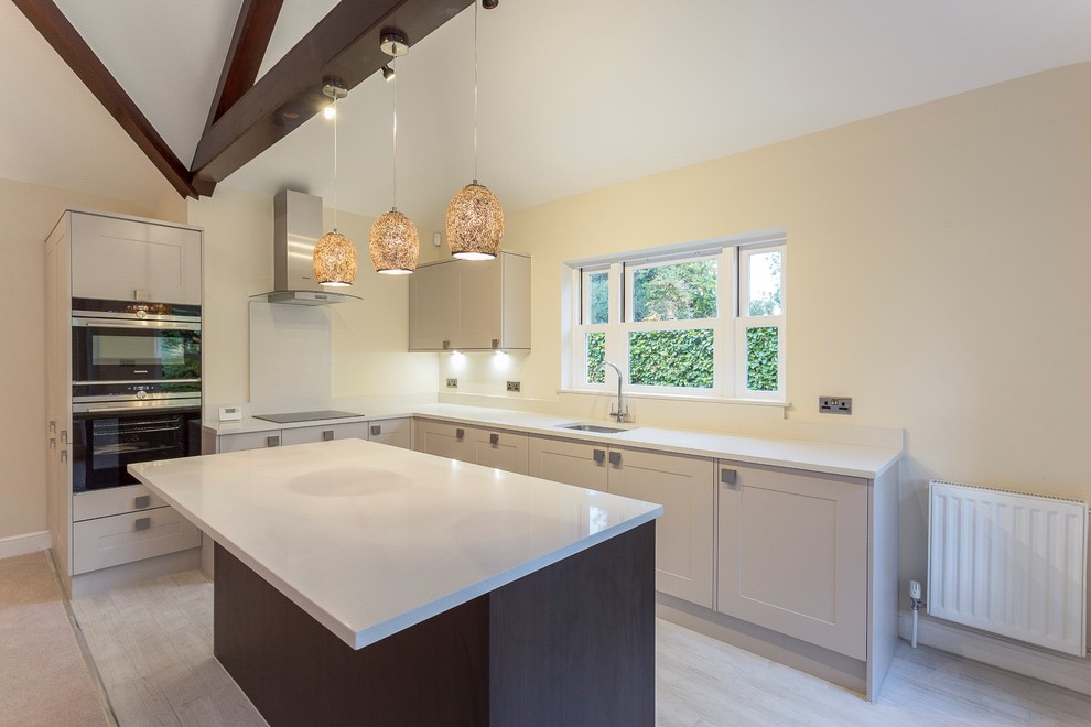 Photo of a mid-sized transitional l-shaped open plan kitchen in London with shaker cabinets and with island.