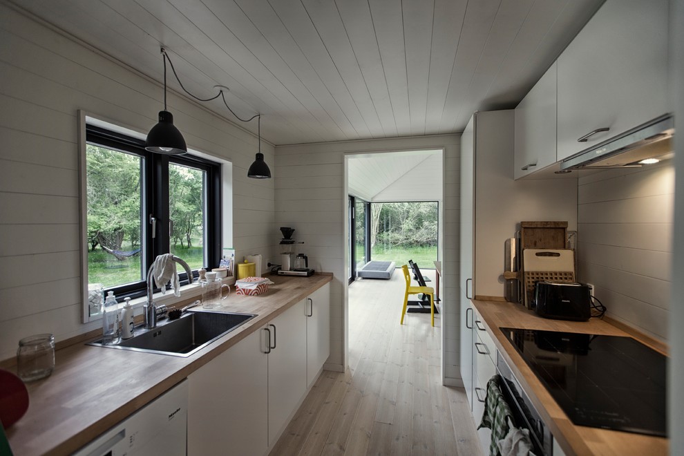 Inspiration for a mid-sized scandinavian galley separate kitchen in Copenhagen with a single-bowl sink, flat-panel cabinets, white cabinets, wood benchtops, stainless steel appliances and no island.