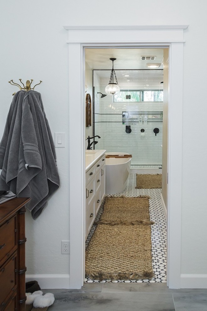 This is an example of a large transitional master bathroom in Phoenix with shaker cabinets, white cabinets, a freestanding tub, a double shower, a two-piece toilet, white tile, glass sheet wall, white walls, porcelain floors, an undermount sink, engineered quartz benchtops, multi-coloured floor, a hinged shower door and white benchtops.
