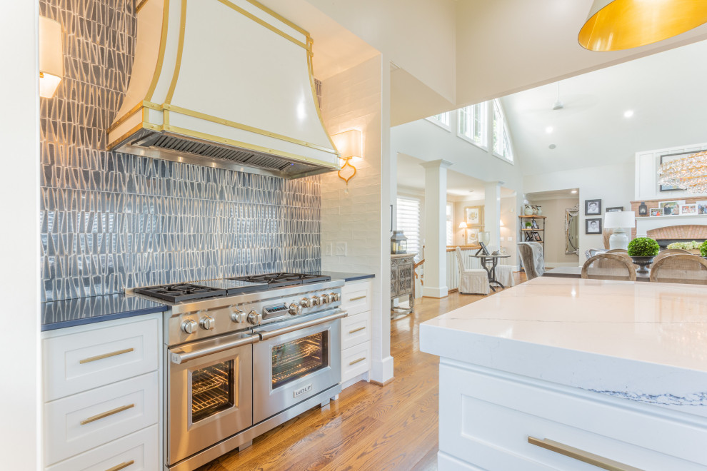 Mid-sized transitional l-shaped eat-in kitchen in Other with a farmhouse sink, shaker cabinets, white cabinets, quartz benchtops, blue splashback, ceramic splashback, stainless steel appliances, medium hardwood floors, with island, brown floor, blue benchtop and vaulted.