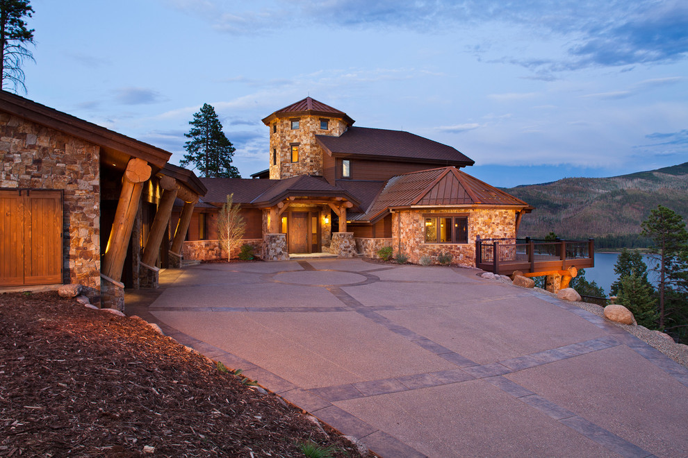Photo of an expansive country split-level brown house exterior in Denver with stone veneer, a hip roof and a mixed roof.