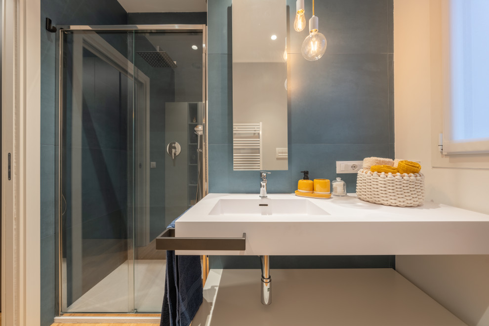 This is an example of a small contemporary master bathroom in Milan with white cabinets, an alcove shower, a two-piece toilet, blue tile, porcelain tile, white walls, light hardwood floors, an integrated sink, solid surface benchtops, beige floor, a sliding shower screen, white benchtops, a single vanity and recessed.