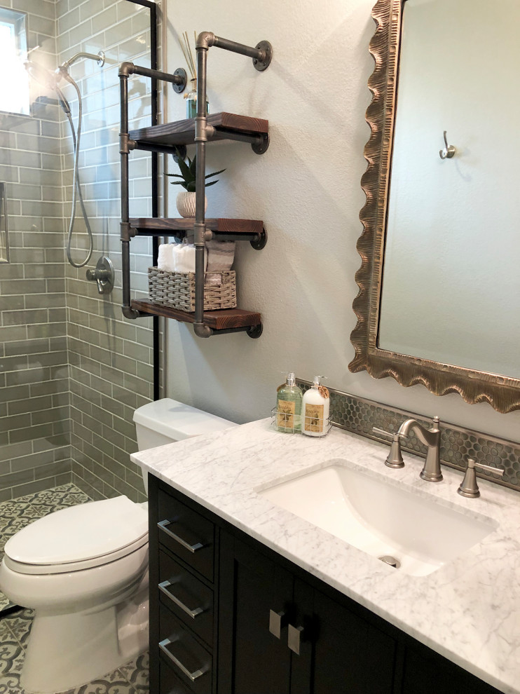 This is an example of a small industrial bathroom in Dallas with shaker cabinets, black cabinets, a curbless shower, a one-piece toilet, brown tile, subway tile, grey walls, porcelain floors, an undermount sink, marble benchtops, multi-coloured floor, an open shower and white benchtops.