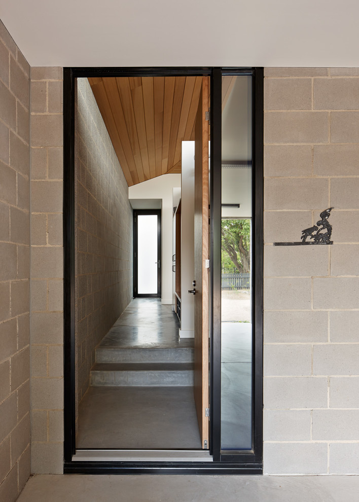 Photo of a contemporary entryway in Melbourne with grey walls, concrete floors and a medium wood front door.