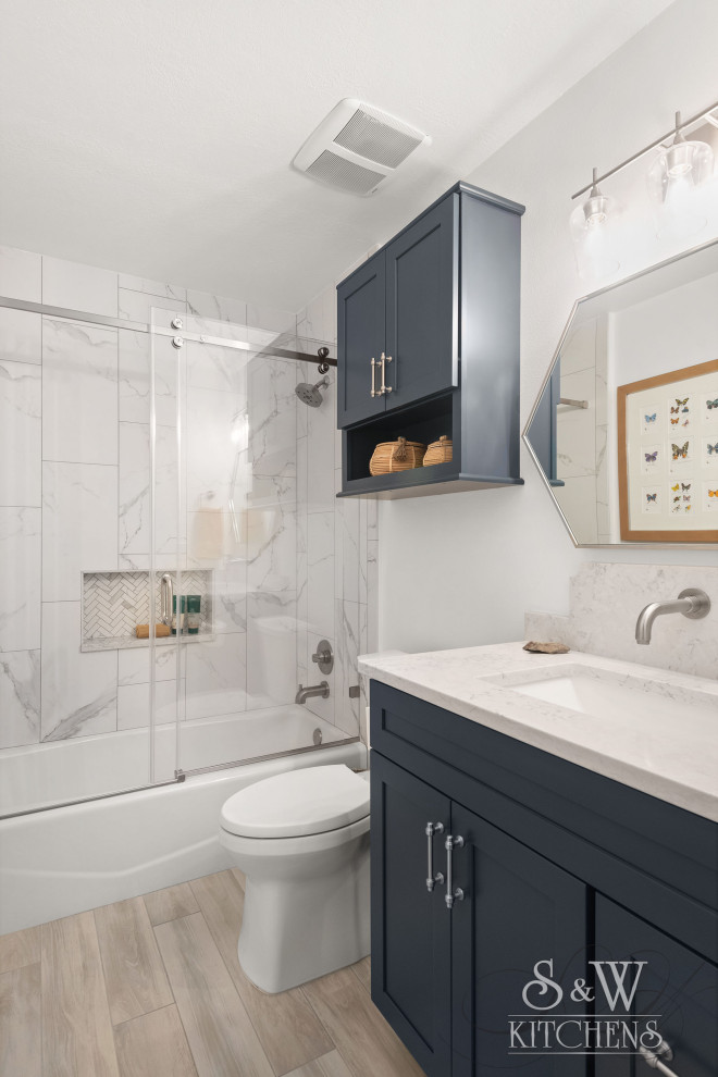 Идея дизайна: маленькая детская ванная комната в скандинавском стиле с фасадами в стиле шейкер, синими фасадами, ванной в нише, душем над ванной, раздельным унитазом, серой плиткой, керамогранитной плиткой, белыми стенами, полом из керамогранита, врезной раковиной, столешницей из искусственного кварца, бежевым полом, душем с раздвижными дверями, серой столешницей, нишей, тумбой под одну раковину и встроенной тумбой для на участке и в саду