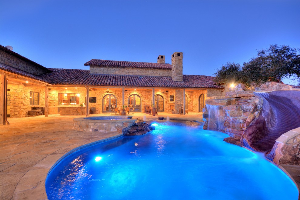 Example of a mountain style backyard stone and custom-shaped natural water slide design in Austin