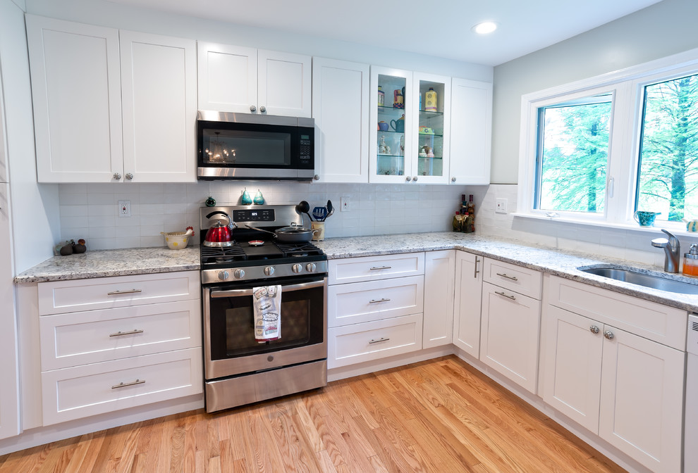 Inspiration for a mid-sized transitional u-shaped eat-in kitchen in Philadelphia with an undermount sink, shaker cabinets, white cabinets, granite benchtops, white splashback, subway tile splashback, stainless steel appliances, light hardwood floors, no island, brown floor and yellow benchtop.