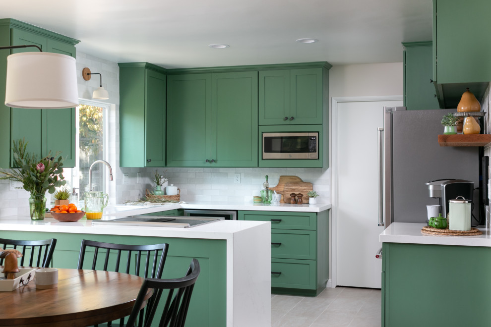 Bild på ett vintage vit vitt kök, med en undermonterad diskho, skåp i shakerstil, gröna skåp, bänkskiva i kvarts, vitt stänkskydd, stänkskydd i tunnelbanekakel, rostfria vitvaror, en halv köksö och grått golv