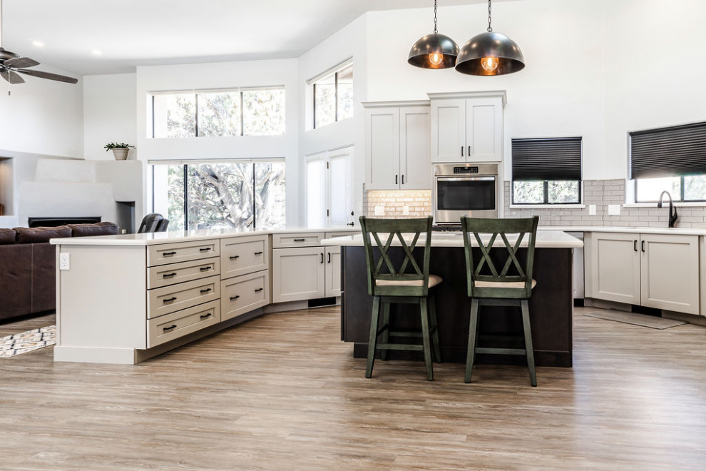 Example of a large transitional u-shaped vinyl floor and gray floor eat-in kitchen design with an undermount sink, shaker cabinets, gray cabinets, quartzite countertops, green backsplash, subway tile backsplash, stainless steel appliances, an island and white countertops