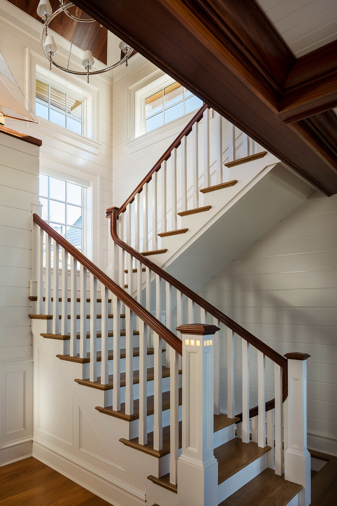 This is an example of a beach style wood u-shaped staircase in New York with painted wood risers and wood railing.