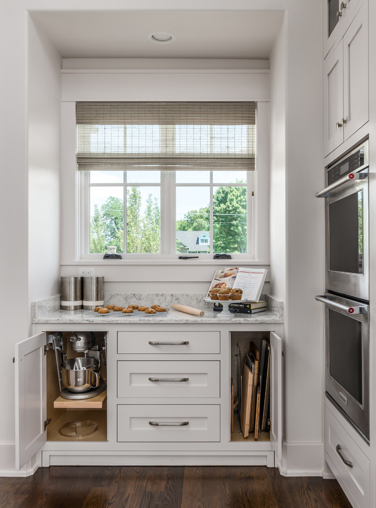 Example of a transitional l-shaped dark wood floor and brown floor open concept kitchen design in Nashville with an undermount sink, beaded inset cabinets, white cabinets, quartz countertops, white backsplash, stone tile backsplash, stainless steel appliances, an island and white countertops