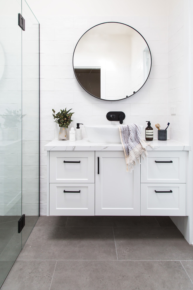 Photo of a mid-sized transitional master bathroom in Melbourne with shaker cabinets, white cabinets, a curbless shower, white tile, white walls, a vessel sink, grey floor, a hinged shower door and white benchtops.