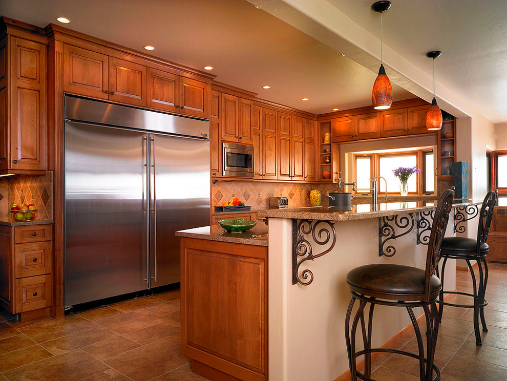 Inspiration for a large transitional u-shaped kitchen in Albuquerque with raised-panel cabinets, medium wood cabinets, beige splashback, stone tile splashback, stainless steel appliances, porcelain floors and with island.