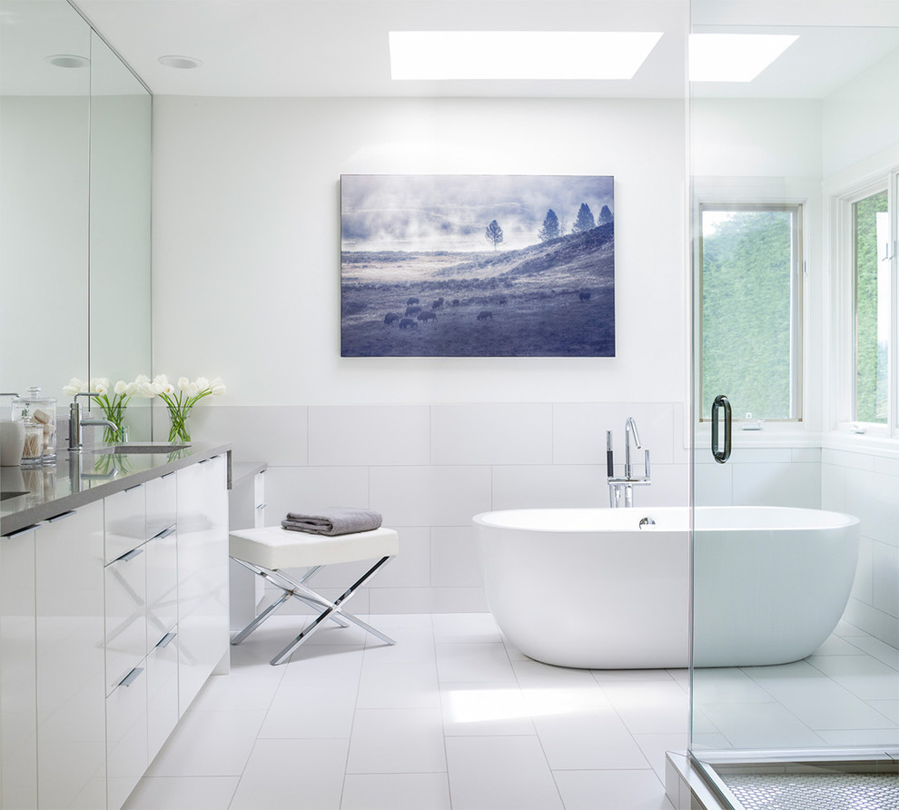 This is an example of a contemporary bathroom in Seattle with an undermount sink, flat-panel cabinets, white cabinets, a freestanding tub, a corner shower, white tile, white walls and grey benchtops.