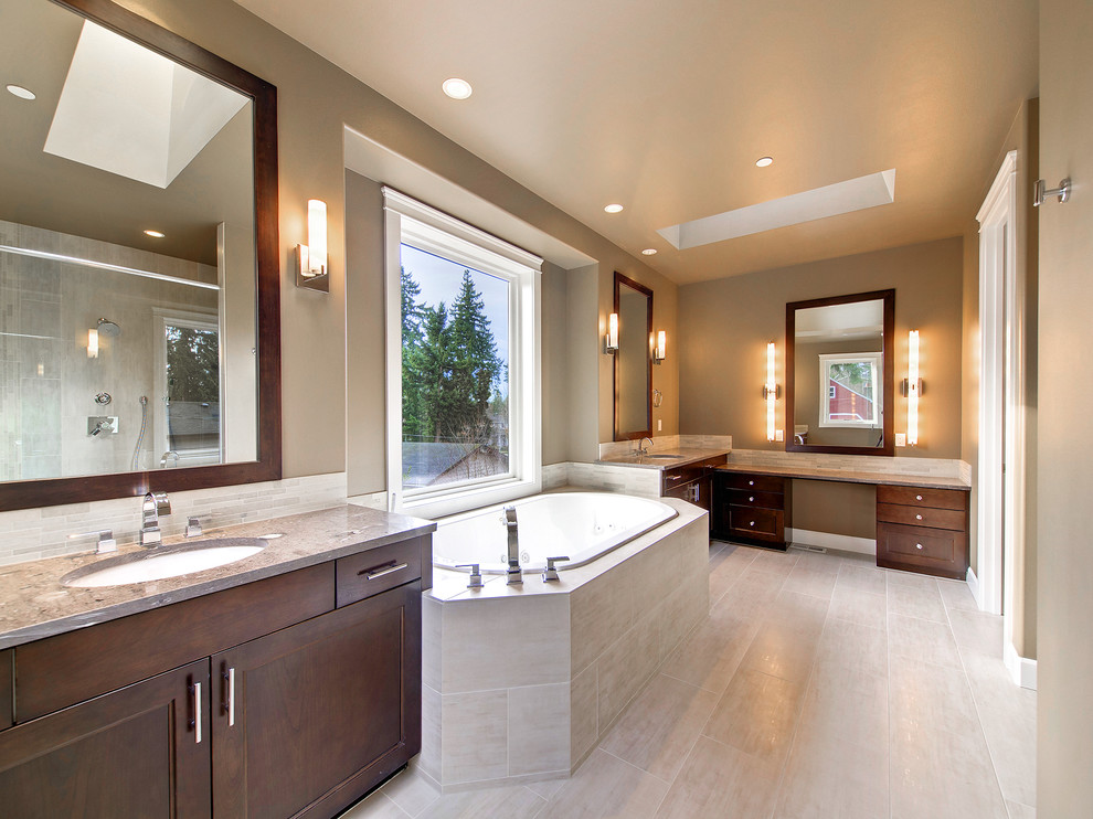 Photo of a contemporary bathroom in Seattle with an undermount sink, shaker cabinets, dark wood cabinets, granite benchtops, a drop-in tub, an alcove shower, a one-piece toilet, beige tile, stone tile and brown walls.