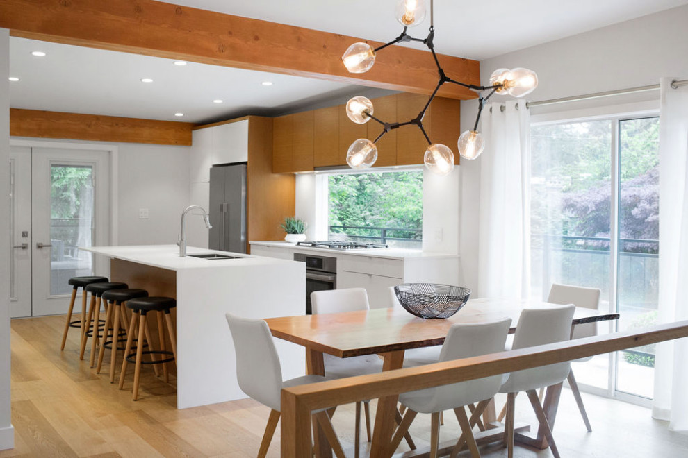 Design ideas for a mid-sized midcentury u-shaped eat-in kitchen in Vancouver with an undermount sink, flat-panel cabinets, medium wood cabinets, quartz benchtops, white splashback, engineered quartz splashback, stainless steel appliances, light hardwood floors, with island, white benchtop and exposed beam.