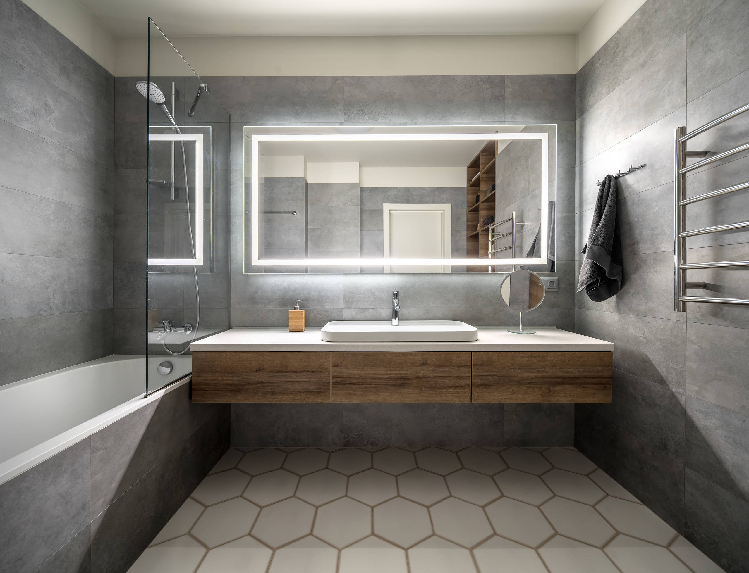 Modern bathroom remodels, with floating vanity and built-in tub. Porcelain concrete looking tiles and LED lighted mirror.