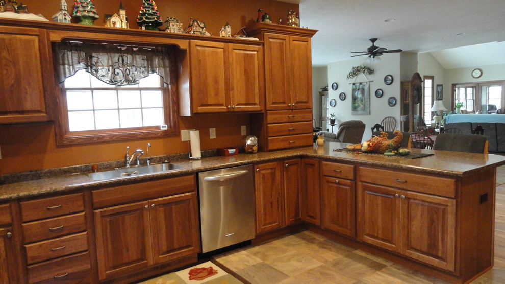 Inspiration for a mid-sized u-shaped open concept kitchen remodel with an undermount sink, raised-panel cabinets, medium tone wood cabinets, laminate countertops, stainless steel appliances, orange walls and a peninsula