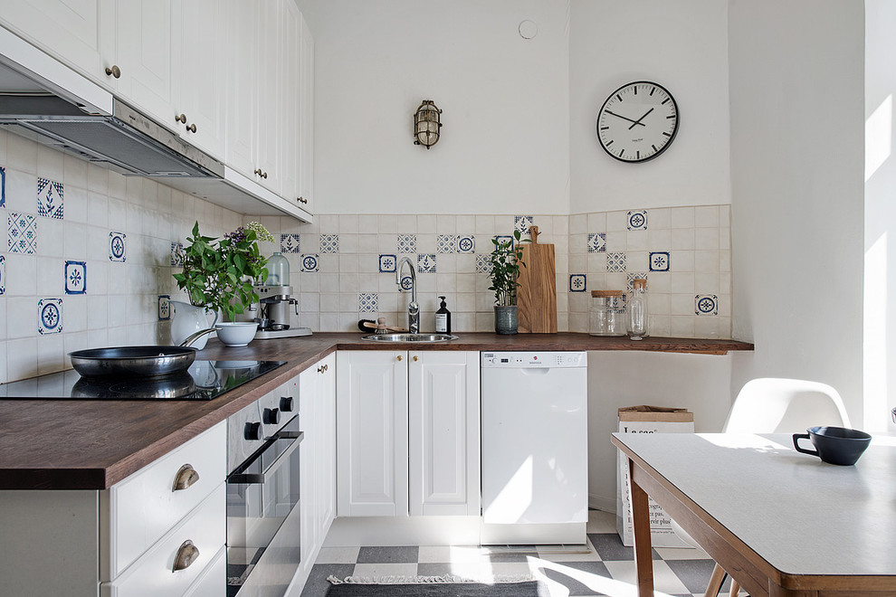 Inspiration for a mid-sized scandinavian l-shaped eat-in kitchen in Gothenburg with a single-bowl sink, raised-panel cabinets, white cabinets, wood benchtops, stainless steel appliances, ceramic floors and no island.