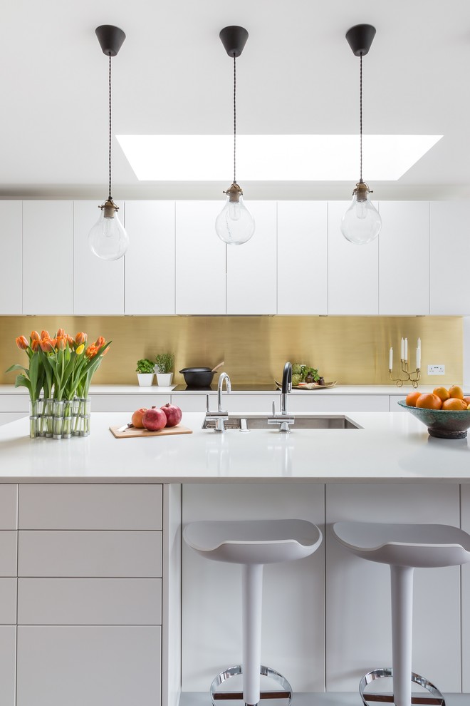 Large contemporary single-wall eat-in kitchen in London with a double-bowl sink, flat-panel cabinets, white cabinets and with island.