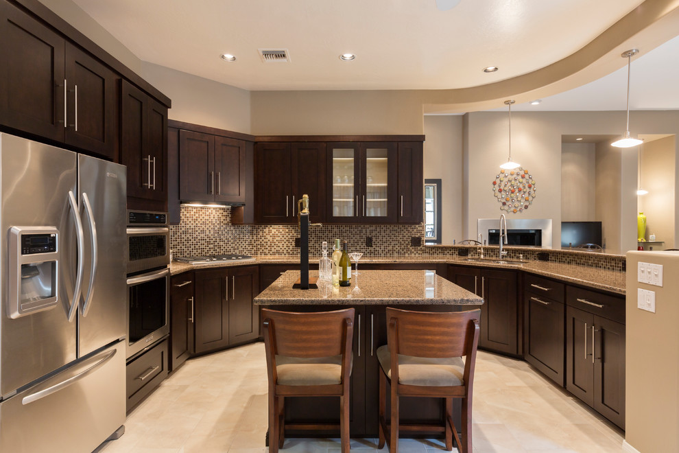 Design ideas for a mid-sized transitional u-shaped separate kitchen in Phoenix with a double-bowl sink, shaker cabinets, brown cabinets, granite benchtops, brown splashback, mosaic tile splashback, stainless steel appliances, travertine floors, with island and beige floor.