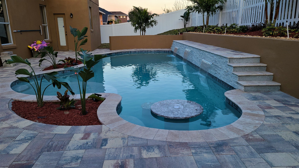 Immagine di una piscina naturale chic personalizzata di medie dimensioni e dietro casa con paesaggistica bordo piscina e pavimentazioni in mattoni