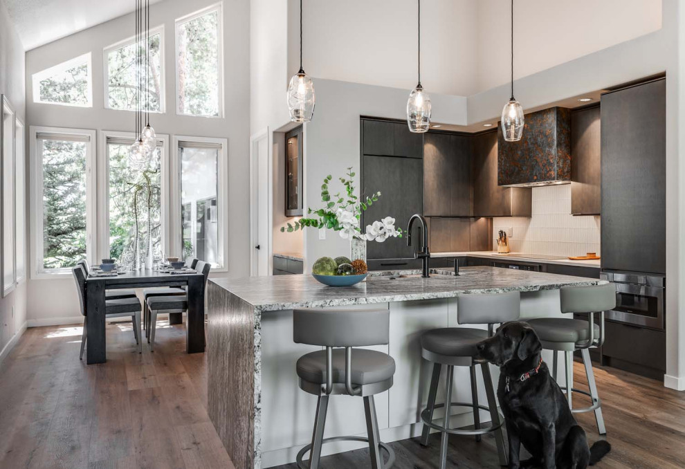 Foto på ett litet funkis flerfärgad kök, med en undermonterad diskho, släta luckor, grå skåp, granitbänkskiva, vitt stänkskydd, stänkskydd i glaskakel, integrerade vitvaror, vinylgolv, en köksö och brunt golv