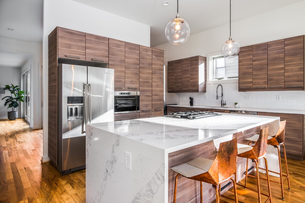 This is an example of a contemporary kitchen in Atlanta with an undermount sink, flat-panel cabinets, dark wood cabinets, white splashback, stainless steel appliances, medium hardwood floors and with island.