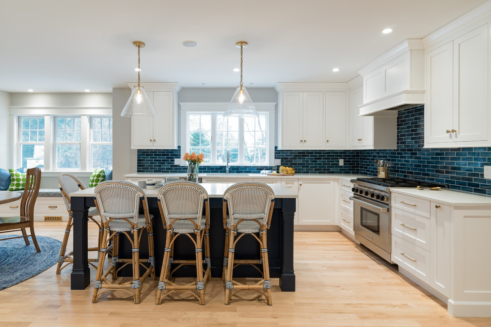 Design ideas for a transitional l-shaped eat-in kitchen in Boston with an undermount sink, shaker cabinets, white cabinets, blue splashback, subway tile splashback, stainless steel appliances, light hardwood floors, with island, beige floor and white benchtop.