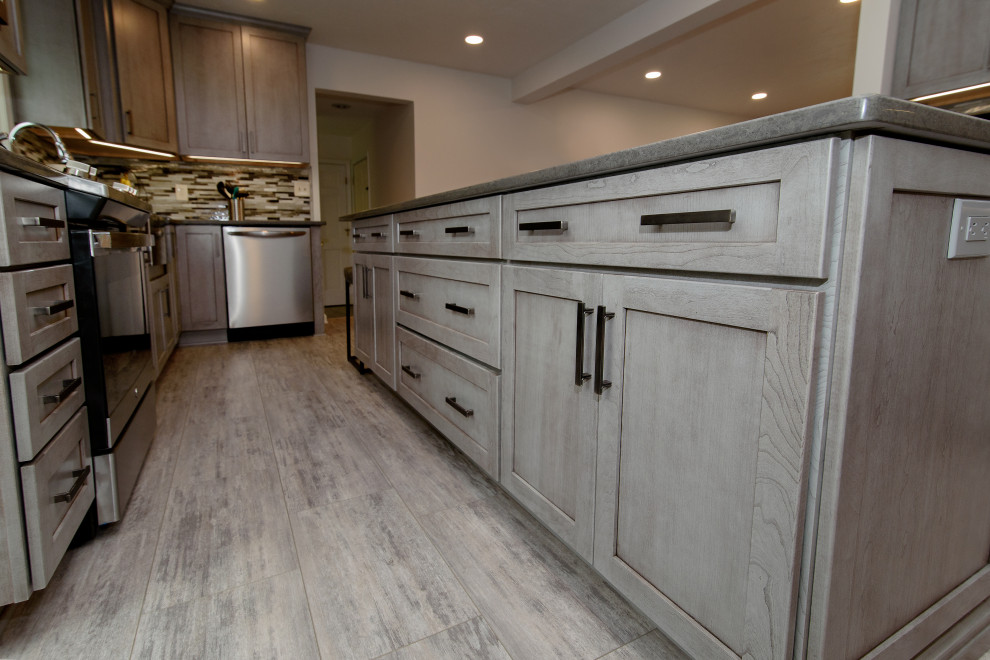 Eat-in kitchen - large transitional u-shaped gray floor eat-in kitchen idea in Baltimore with a farmhouse sink, shaker cabinets, gray cabinets, quartz countertops, multicolored backsplash, glass tile backsplash, stainless steel appliances, an island and gray countertops